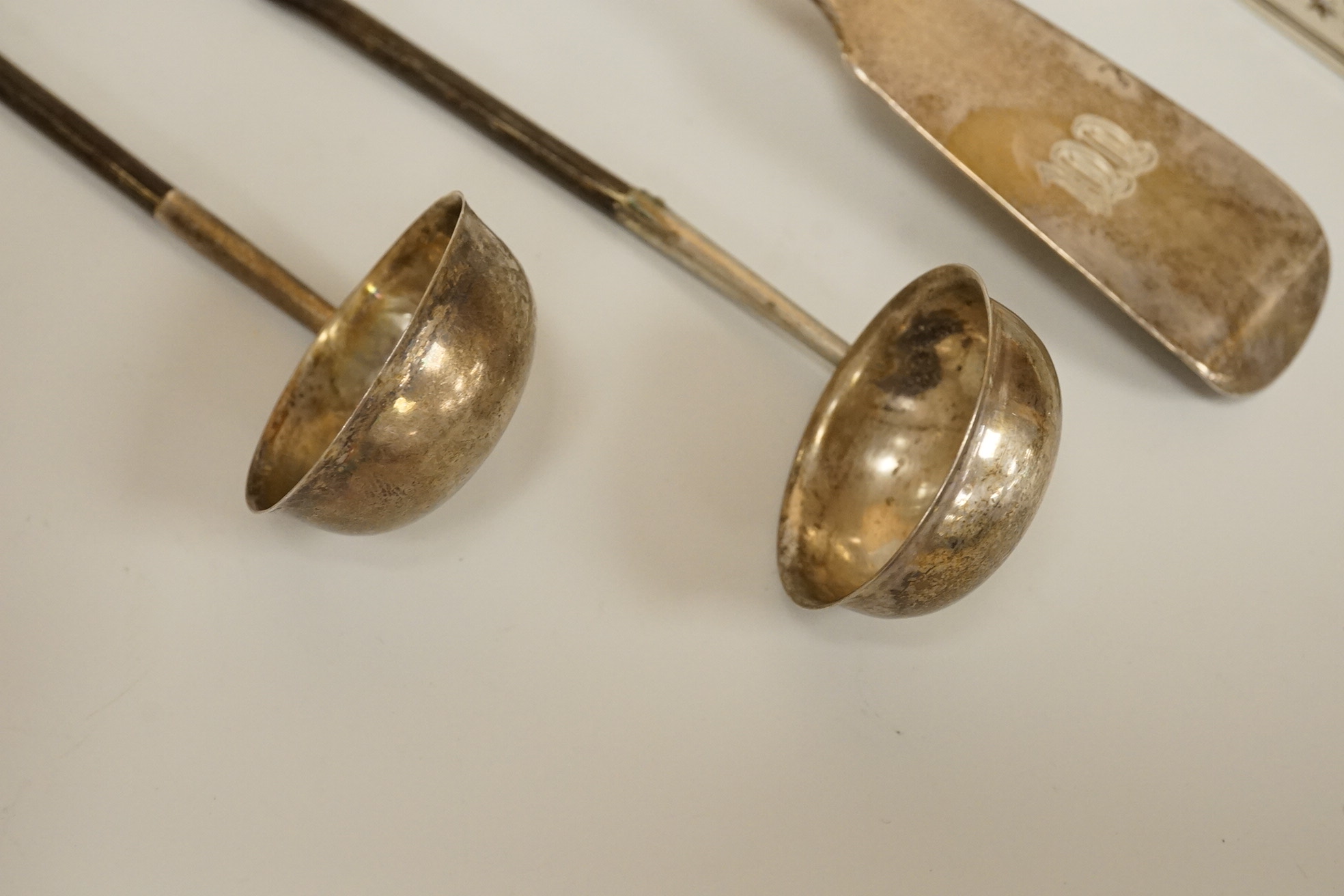 A pair of William IV silver fiddle, thread and shall pattern asparagus servers, a George IV silver fiddle pattern basting spoon, Robert Gainsford, Sheffield, 1826, 31.2cm, 10.8oz and two 19th century white metal toddy la